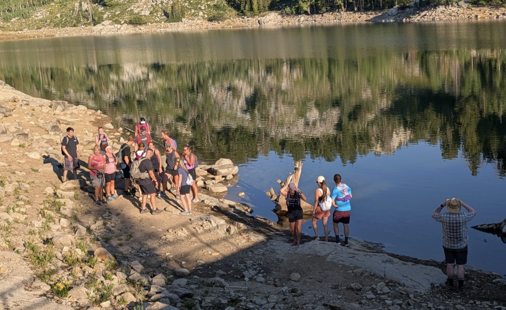 Singles hike participants gathered beside a mountain lake in Utah